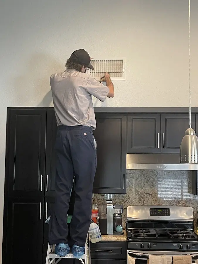 Technician inspecting an air vent during HVAC service in Lyons